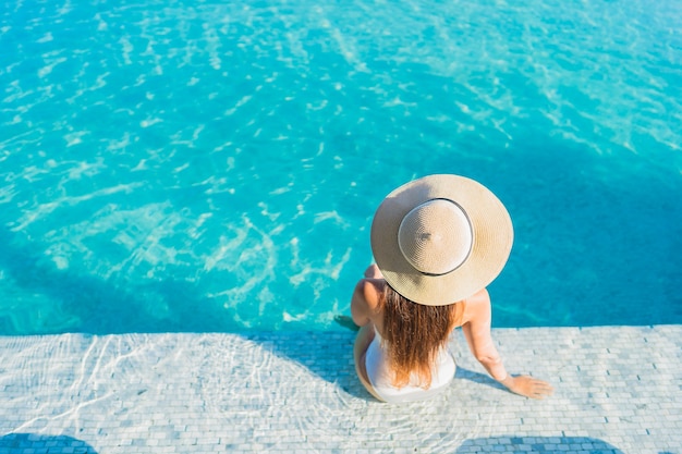 Retrato hermosa joven asiática relajante alrededor de la piscina al aire libre con vistas a la ciudad