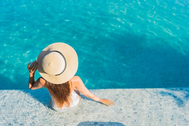 Retrato hermosa joven asiática relajante alrededor de la piscina al aire libre con vistas a la ciudad