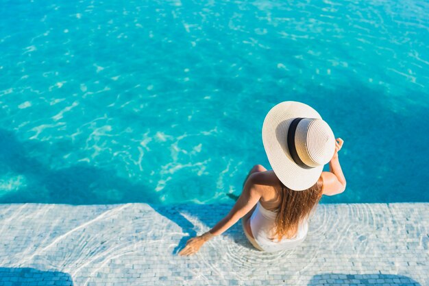 Retrato hermosa joven asiática relajante alrededor de la piscina al aire libre con vistas a la ciudad