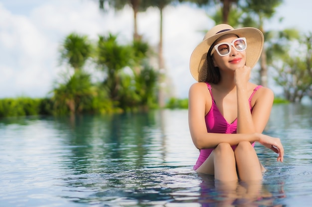 Foto gratuita retrato hermosa joven asiática relajarse disfrutar alrededor de la piscina al aire libre en vacaciones de vacaciones