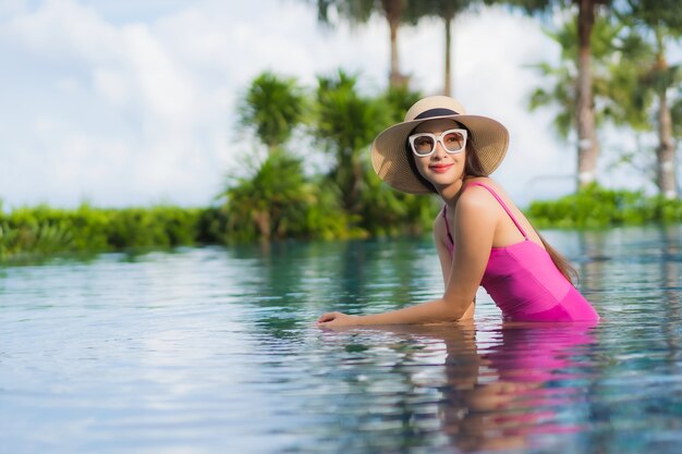 Retrato hermosa joven asiática relajarse disfrutar alrededor de la piscina al aire libre en vacaciones de vacaciones