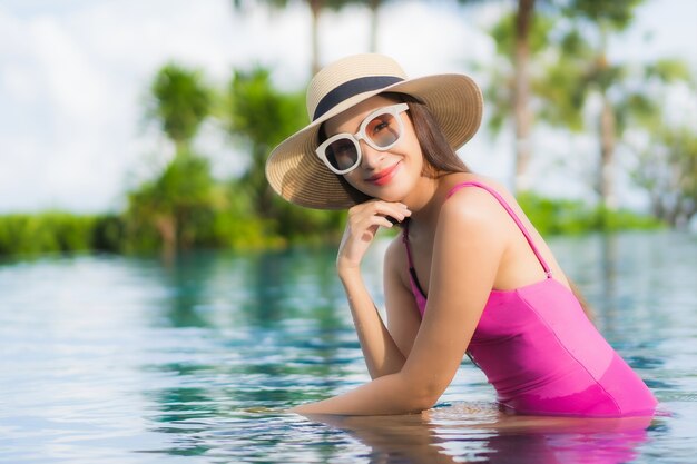 Foto gratuita retrato hermosa joven asiática relajarse disfrutar alrededor de la piscina al aire libre en vacaciones de vacaciones