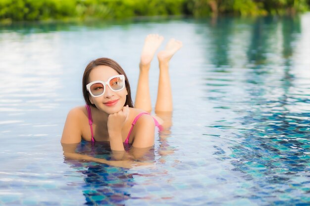 Retrato hermosa joven asiática relajarse disfrutar alrededor de la piscina al aire libre en vacaciones de vacaciones