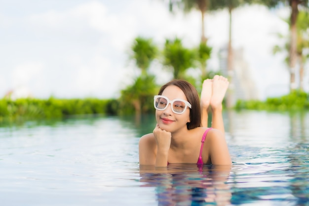 Retrato hermosa joven asiática relajarse disfrutar alrededor de la piscina al aire libre en vacaciones de vacaciones