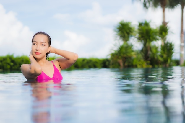 Retrato hermosa joven asiática relajarse disfrutar alrededor de la piscina al aire libre en vacaciones de vacaciones