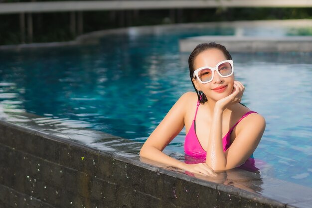 Retrato hermosa joven asiática relajarse disfrutar alrededor de la piscina al aire libre en vacaciones de vacaciones