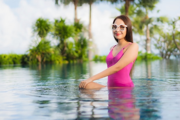 Retrato hermosa joven asiática relajarse disfrutar alrededor de la piscina al aire libre en vacaciones de vacaciones