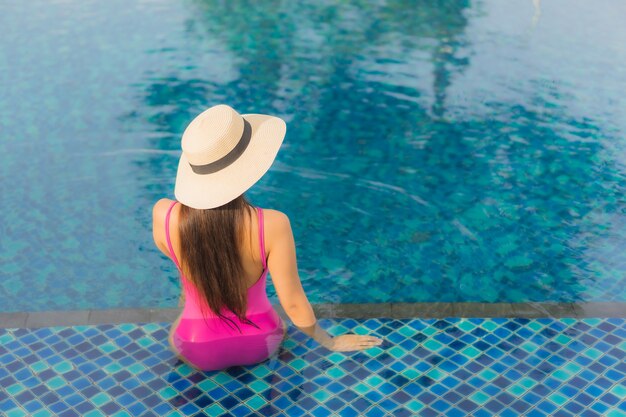 Retrato hermosa joven asiática relajarse disfrutar alrededor de la piscina al aire libre en vacaciones de vacaciones