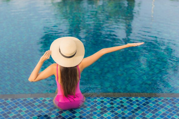 Retrato hermosa joven asiática relajarse disfrutar alrededor de la piscina al aire libre en vacaciones de vacaciones