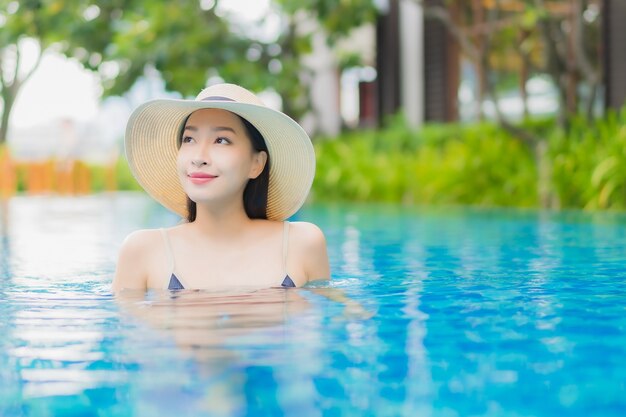 Retrato hermosa joven asiática relajarse disfrutar de una sonrisa alrededor de la piscina al aire libre en el hotel resort en vacaciones de ocio