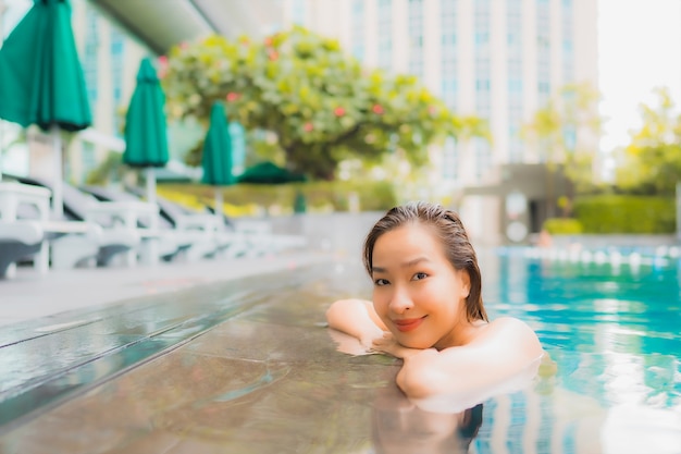 Retrato hermosa joven asiática relajarse feliz sonrisa ocio alrededor de la piscina al aire libre