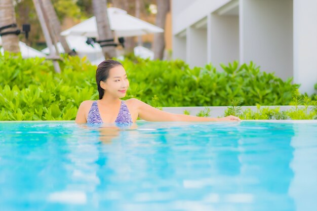 Retrato hermosa joven asiática relajarse ocio alrededor de la piscina al aire libre con mar océano playa