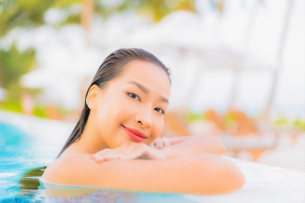 Retrato hermosa joven asiática relajarse ocio alrededor de la piscina al aire libre con mar océano playa