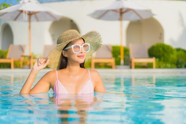 Retrato hermosa joven asiática relajarse ocio alrededor de la piscina al aire libre con mar