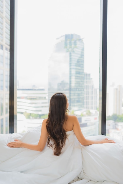 Retrato hermosa joven asiática relajarse ocio en la cama con vistas a la ciudad