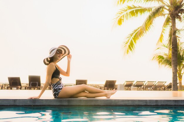 Retrato hermosa joven asiática relajarse en la piscina al aire libre en el hotel resort con palmera al atardecer o al amanecer