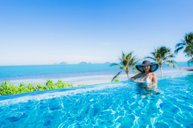 Retrato hermosa joven asiática relajarse en la piscina al aire libre de lujo en el hotel resort casi playa mar océano
