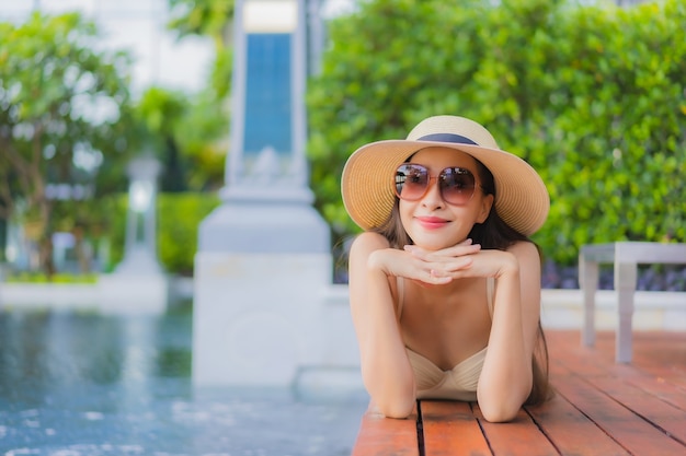 Retrato hermosa joven asiática relajarse sonrisa alrededor de la piscina al aire libre en el hotel resort en viajes de vacaciones