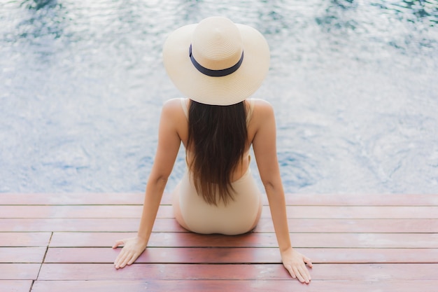 Retrato hermosa joven asiática relajarse sonrisa alrededor de la piscina al aire libre en el hotel resort en viajes de vacaciones