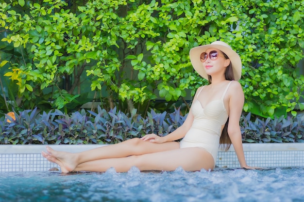 Retrato hermosa joven asiática relajarse sonrisa alrededor de la piscina al aire libre en el hotel resort en viajes de vacaciones