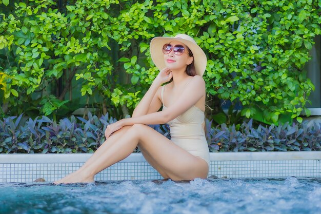 Retrato hermosa joven asiática relajarse sonrisa alrededor de la piscina al aire libre en el hotel resort en viajes de vacaciones