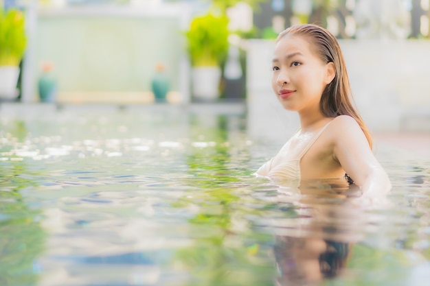 Retrato hermosa joven asiática relajarse sonrisa alrededor de la piscina al aire libre en el hotel resort en viajes de vacaciones