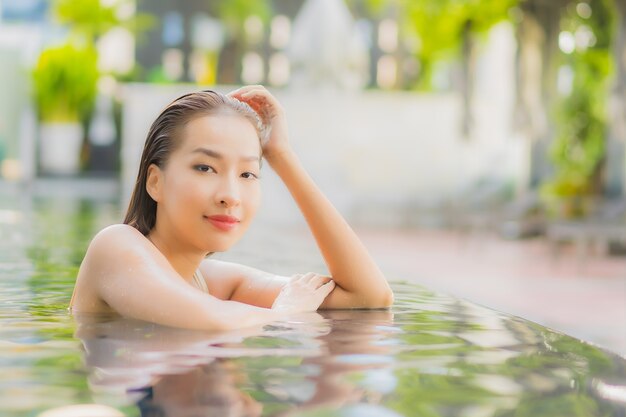 Retrato hermosa joven asiática relajarse sonrisa alrededor de la piscina al aire libre en el hotel resort en viajes de vacaciones