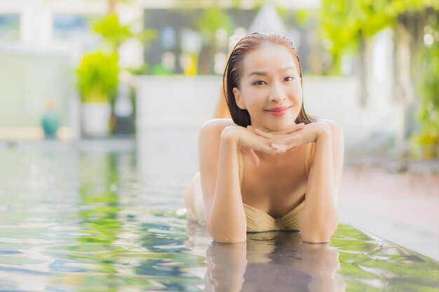 Retrato hermosa joven asiática relajarse sonrisa alrededor de la piscina al aire libre en el hotel resort en viajes de vacaciones