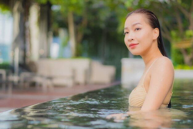 Retrato hermosa joven asiática relajarse sonrisa alrededor de la piscina al aire libre en el hotel resort en viajes de vacaciones