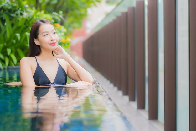 Retrato hermosa joven asiática relajarse sonrisa alrededor de la piscina al aire libre en el hotel resort