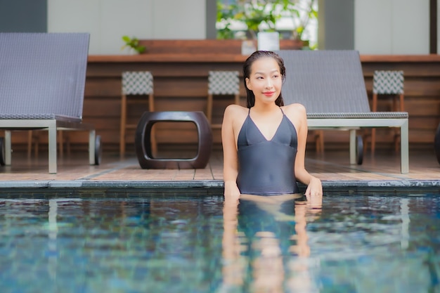 Retrato hermosa joven asiática relajarse sonrisa alrededor de la piscina al aire libre en el hotel resort