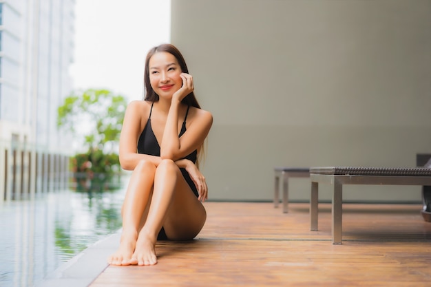 Retrato hermosa joven asiática relajarse sonrisa alrededor de la piscina al aire libre en el hotel resort