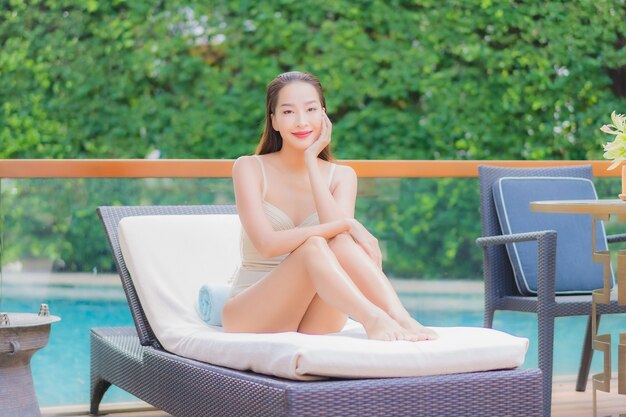 Retrato hermosa joven asiática relajarse sonrisa alrededor de la piscina al aire libre en el hotel resort