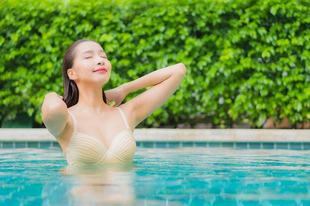 Retrato hermosa joven asiática relajarse sonrisa alrededor de la piscina al aire libre en el hotel resort