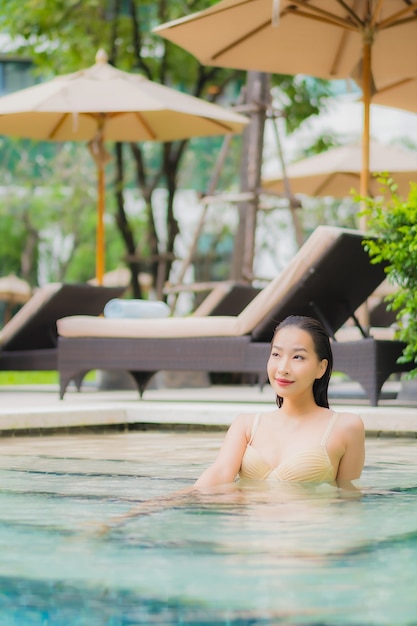 Retrato hermosa joven asiática relajarse sonrisa alrededor de la piscina al aire libre en el hotel resort