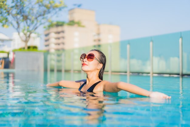 Retrato hermosa joven asiática relajarse sonrisa alrededor de la piscina al aire libre en el hotel resort