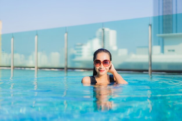 Retrato hermosa joven asiática relajarse sonrisa alrededor de la piscina al aire libre en el hotel resort