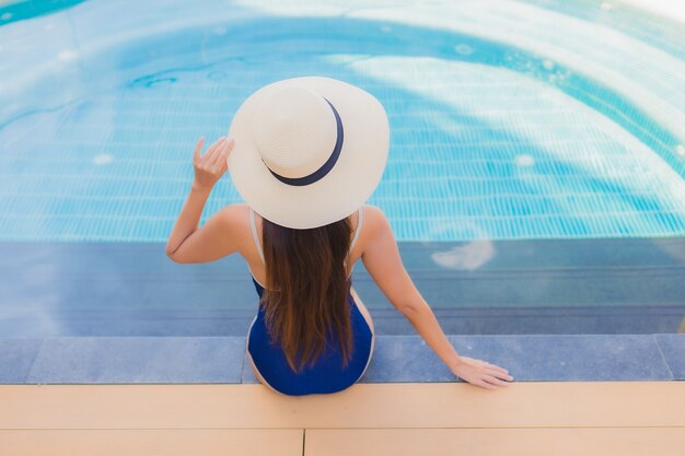 Retrato hermosa joven asiática relajarse sonrisa alrededor de la piscina al aire libre en el hotel resort