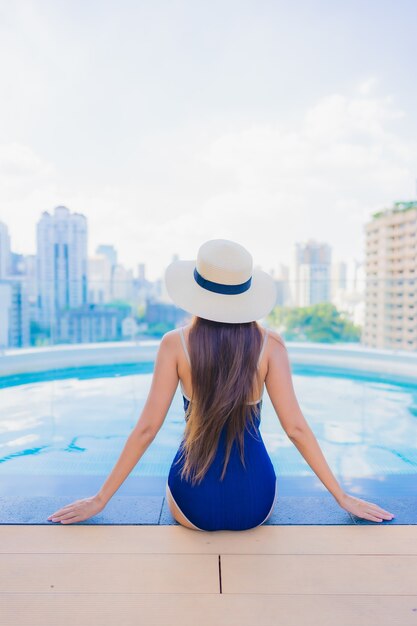 Retrato hermosa joven asiática relajarse sonrisa alrededor de la piscina al aire libre en el hotel resort