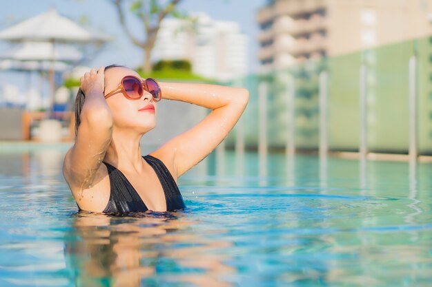 Retrato hermosa joven asiática relajarse sonrisa alrededor de la piscina al aire libre en el hotel resort