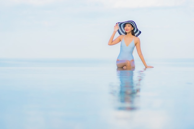 Retrato hermosa joven asiática relajarse sonrisa alrededor de la piscina al aire libre en el hotel resort