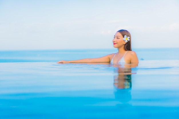 Retrato hermosa joven asiática relajarse sonrisa alrededor de la piscina al aire libre en el hotel resort