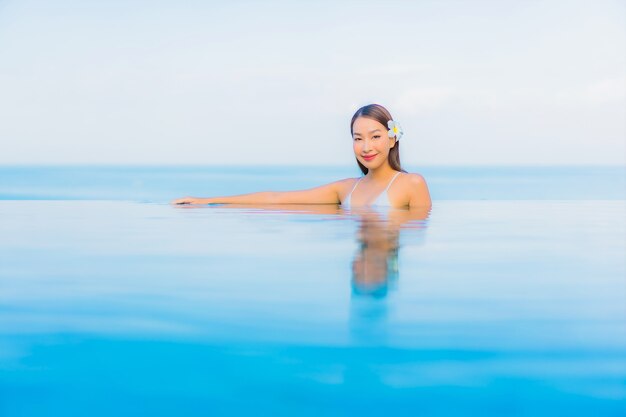 Retrato hermosa joven asiática relajarse sonrisa alrededor de la piscina al aire libre en el hotel resort