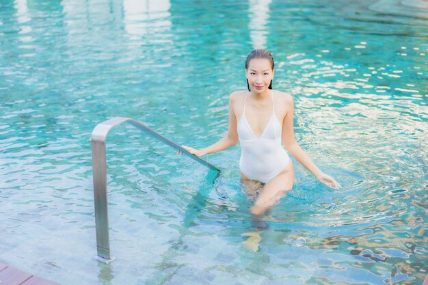 Retrato hermosa joven asiática relajarse sonrisa alrededor de la piscina al aire libre en el hotel resort