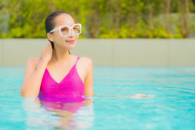 Retrato hermosa joven asiática relajarse sonrisa alrededor de la piscina al aire libre en el hotel resort