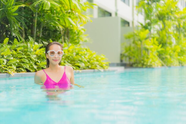 Retrato hermosa joven asiática relajarse sonrisa alrededor de la piscina al aire libre en el hotel resort