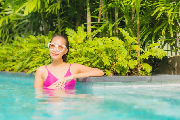 Retrato hermosa joven asiática relajarse sonrisa alrededor de la piscina al aire libre en el hotel resort