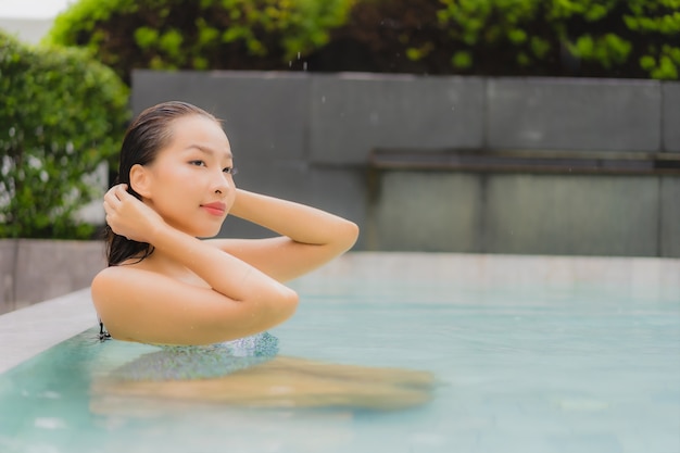 Retrato hermosa joven asiática relajarse sonrisa alrededor de la piscina al aire libre para el ocio y las vacaciones