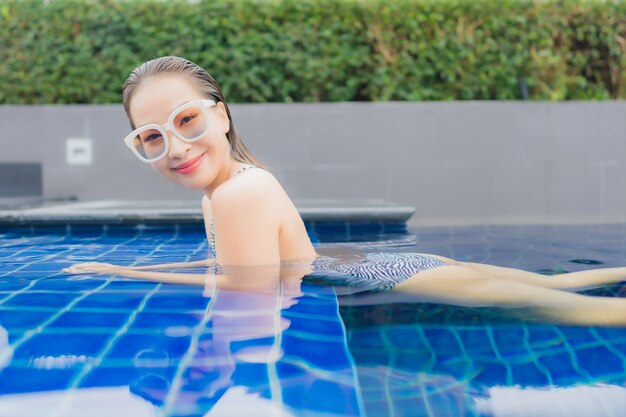 Retrato hermosa joven asiática relajarse sonrisa alrededor de la piscina al aire libre