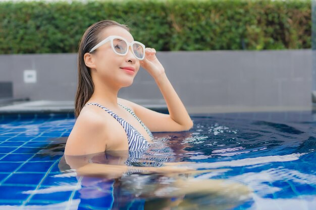 Retrato hermosa joven asiática relajarse sonrisa alrededor de la piscina al aire libre